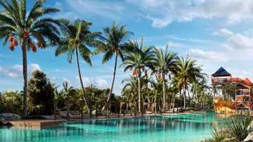 Piscinas do resort com palmeiras, áreas de descanso e toboágua